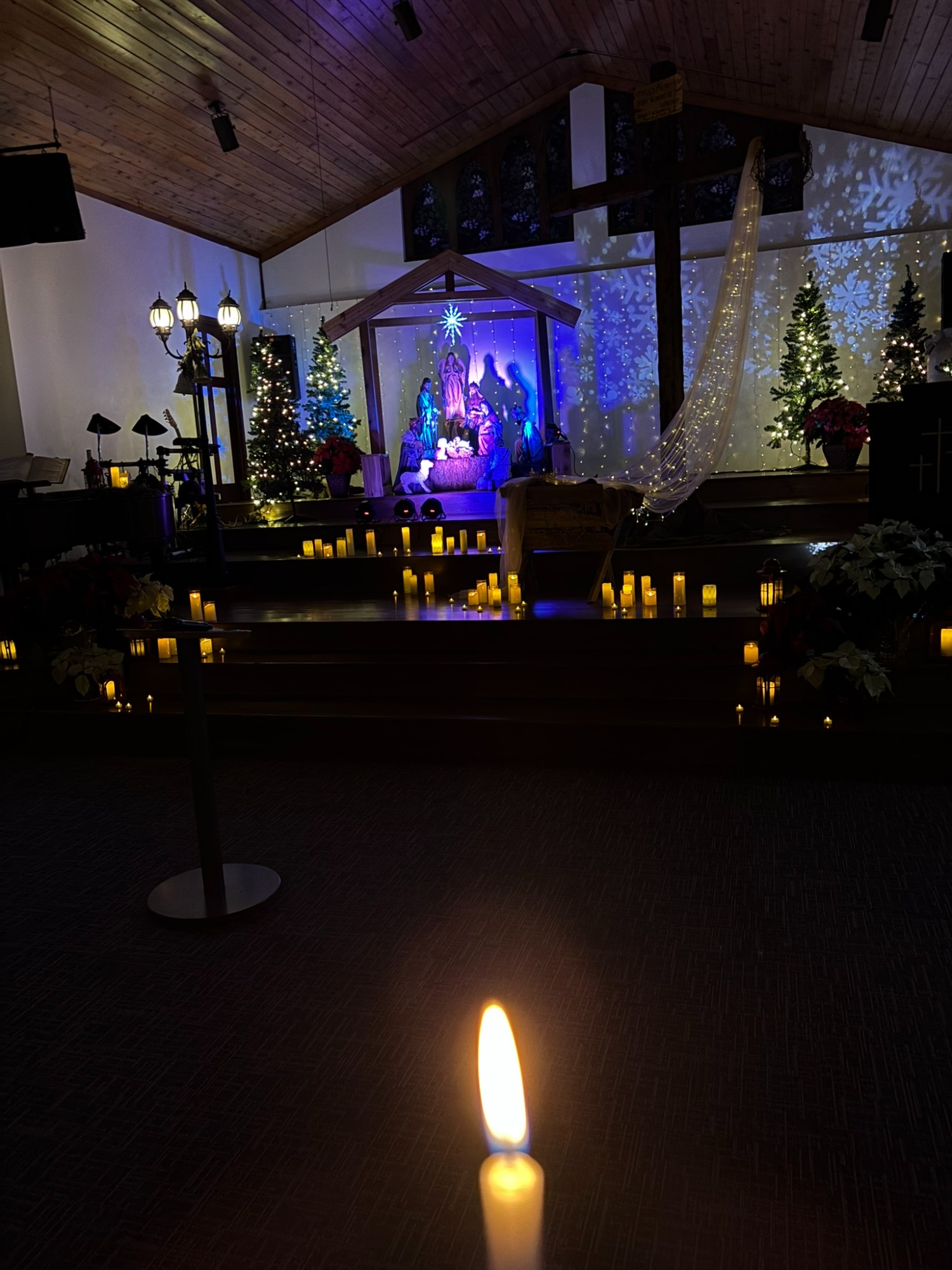 Christmas candle glowing before the nativity scene